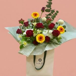 colorful floral harmony – red roses & mixed blooms in white bag