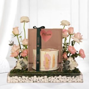 mom's sweet magic personalized cake inside a transparent acrylic box arranged with white ranunculus, hydrangeas, pink spray roses and also the unique mom's topper